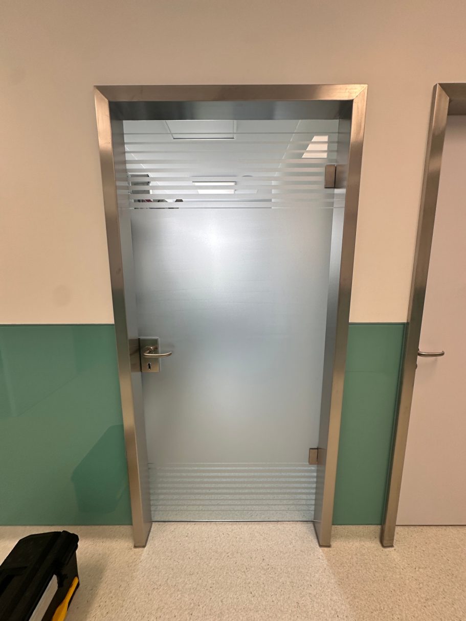 Glatte Glasschiebetür mit silbernem Rahmen in einem modernen Innenraum.